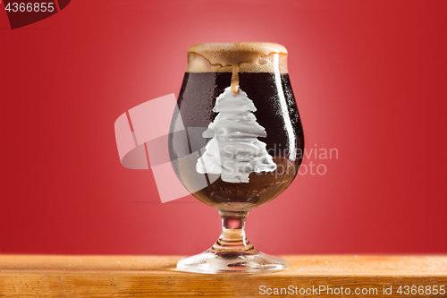 Image of glass of cold frothy dark beer on an old wooden table