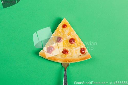 Image of Slice of pizza on a fork on a green background