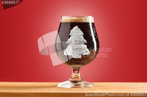 Image of glass of cold frothy dark beer on an old wooden table