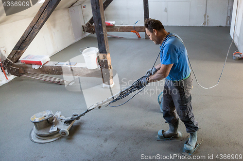 Image of Laborer polishing sand and cement screed floor.