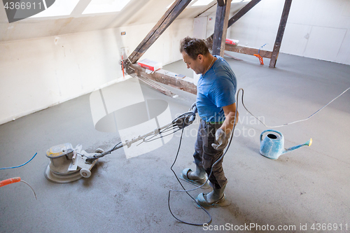 Image of Laborer polishing sand and cement screed floor.