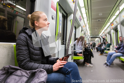 Image of Young girl with mobile phone traveling on metro.