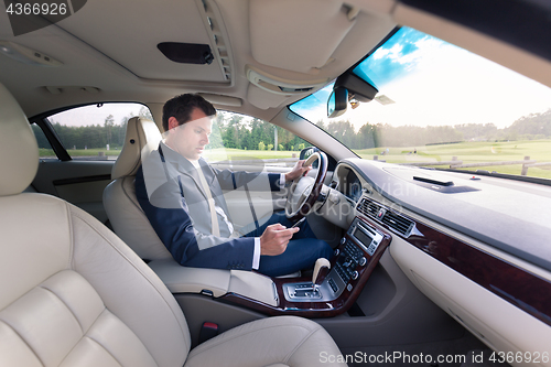 Image of Businessman using cell phone and texting while driving not paying attention to the road.