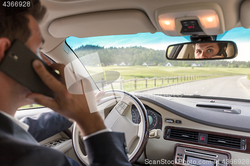 Image of Man talking on cell phone while driving not paying attention to the road.