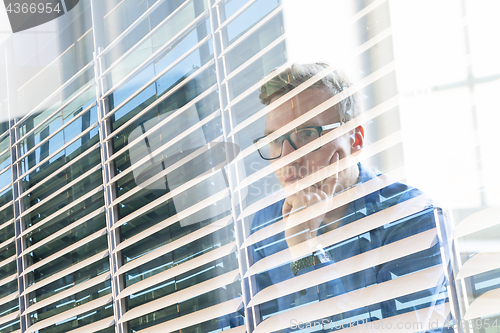 Image of Casual businessman working in office, sitting at desk, typing on keyboard, looking at computer screen.