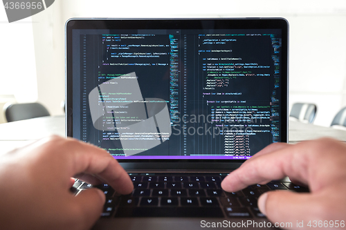 Image of Programmer profession - man writing programming code on laptop computer.