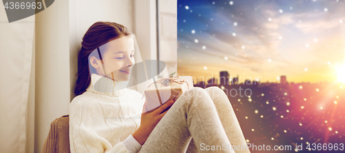 Image of girl with christmas gift on window sill in winter