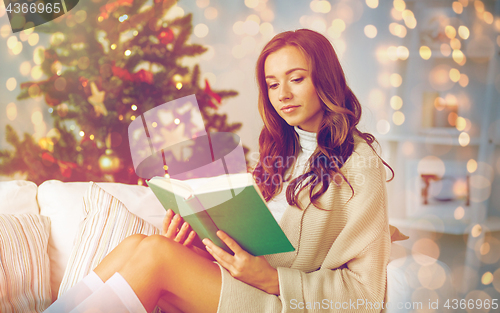 Image of happy woman reading book at home for christmas
