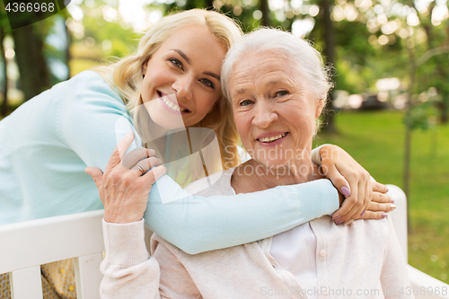 Image of daughter with senior mother hugging on park bench