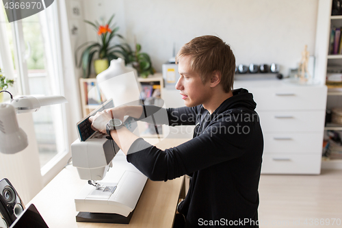 Image of fashion designer with sewing machine at studio