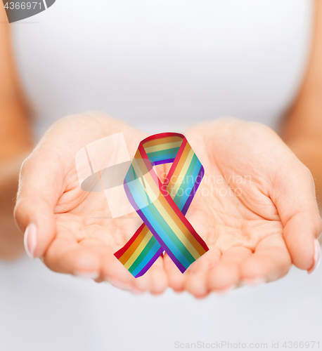 Image of female hands holding gay pride awareness ribbon