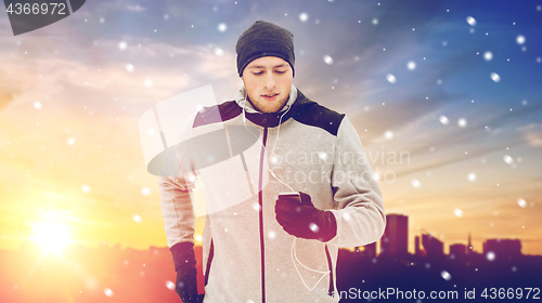 Image of happy man with earphones and smartphone in winter