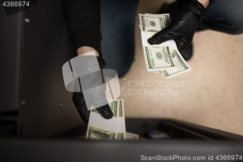 Image of thief stealing money from safe at crime scene