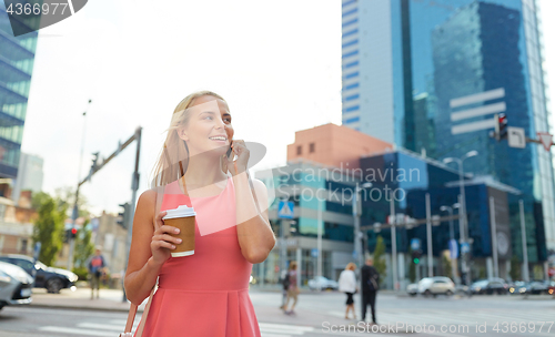 Image of woman with coffee calling on smartphone in city