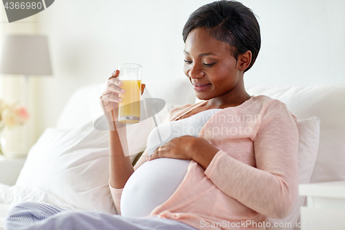 Image of pregnant woman drinking orange juice in bed