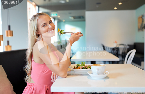 Image of happy young woman eating lunch at restaurant