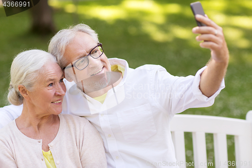 Image of senior couple taking selfie by smartphone at park