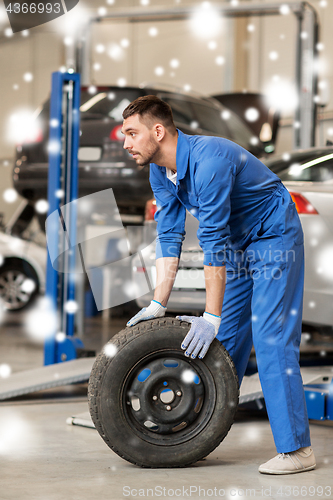 Image of auto mechanic changing car tire at workshop