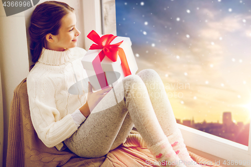 Image of girl with christmas gift on window sill in winter