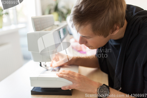 Image of fashion designer with sewing machine at studio