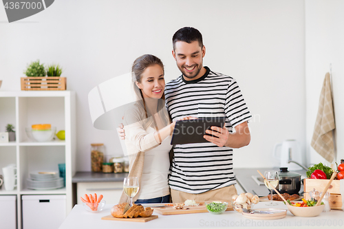 Image of happy couple with tablet pc cooking food at home