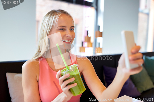 Image of woman with smartphone taking selfie at restaurant