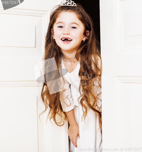 Image of little cute girl at home, opening door well-dressed in white dre