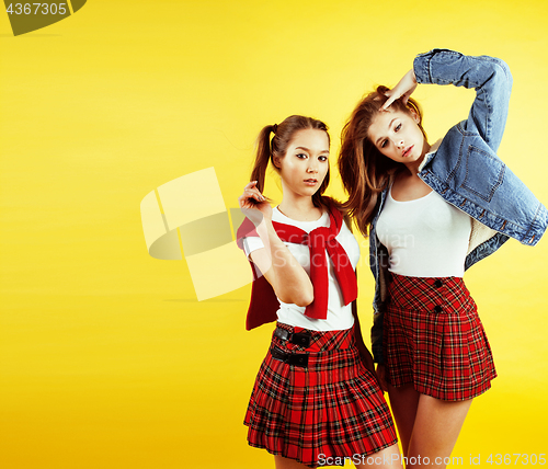 Image of lifestyle people concept: two pretty young school teenage girls having fun happy smiling on yellow background