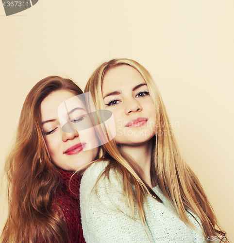 Image of Two young girlfriends in winter sweaters indoors having fun. Lif