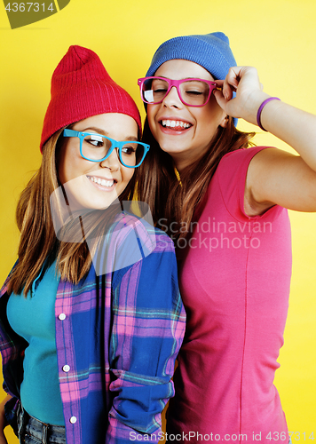 Image of lifestyle people concept: two pretty young school teenage girls having fun happy smiling on yellow background