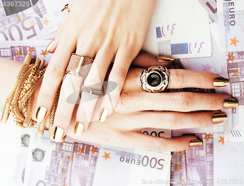 Image of hands of rich woman with golden manicure and many jewelry rings on cash euros
