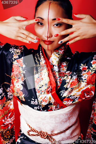 Image of young pretty geisha on red background posing in kimono, oriental people concept close up