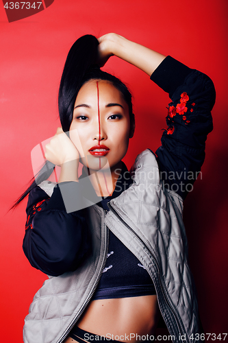 Image of young pretty asian girl posing cheerful on red background, fashion style makeup and hair, lifestyle modern orient people concept