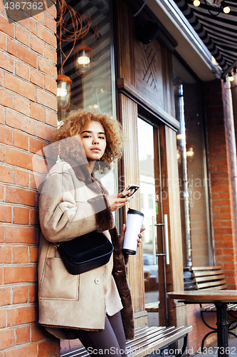 Image of young pretty african american women drinking coffee outside in c