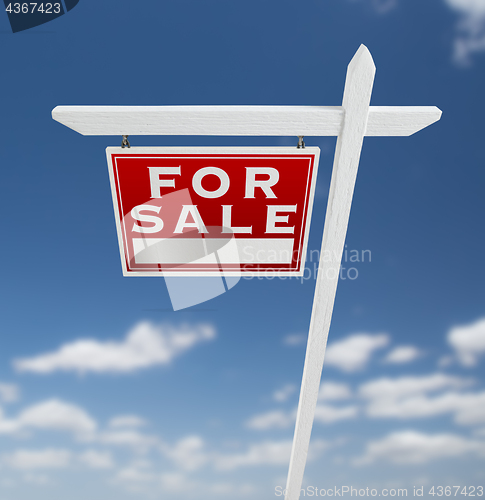 Image of Left Facing For Sale Real Estate Sign on a Blue Sky with Clouds.