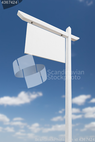 Image of Blank Real Estate Sign Over A Blue Sky with Clouds.