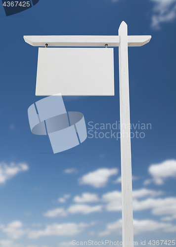 Image of Blank Real Estate Sign Over A Blue Sky with Clouds.