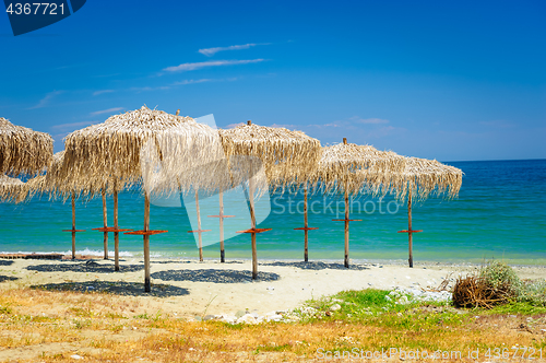 Image of reed umbrellas at empty beach