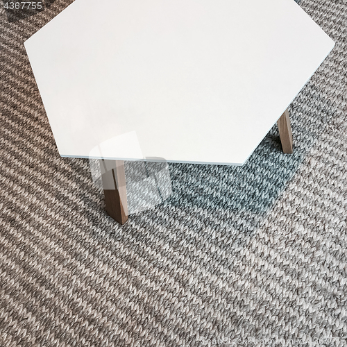 Image of Modern white table on gray knitted rug