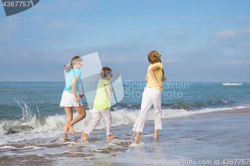 Image of Three happy children running on the beach at the day time.