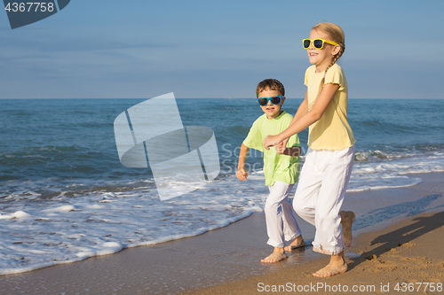 Image of Two happy children running on the beach at the day time.