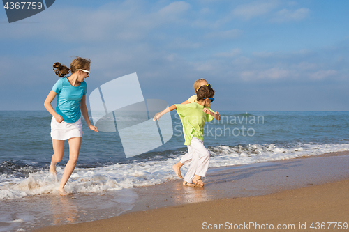 Image of Three happy children running on the beach at the day time.