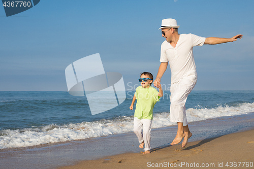 Image of Father and son running on the beach at the day time.