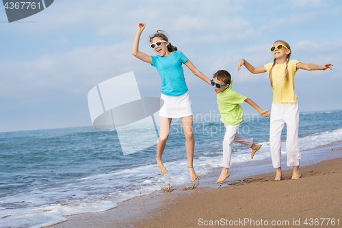 Image of Three happy children running on the beach at the day time.