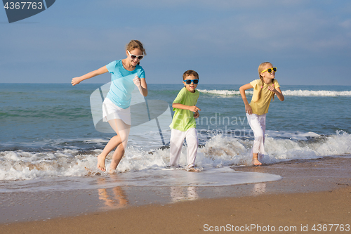 Image of Three happy children running on the beach at the day time.