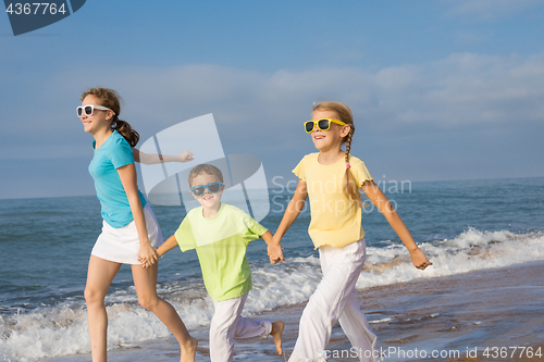 Image of Three happy children running on the beach at the day time.