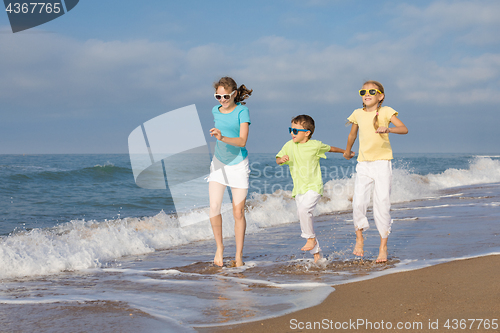 Image of Three happy children running on the beach at the day time.