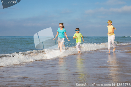 Image of Three happy children running on the beach at the day time.