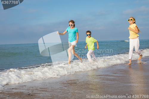 Image of Three happy children running on the beach at the day time.