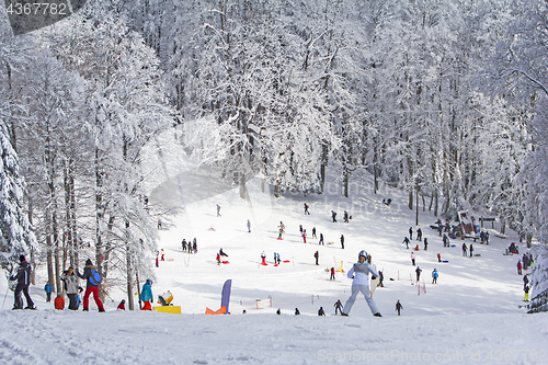 Image of Group kids and people sledding and skiing in the snow in the win